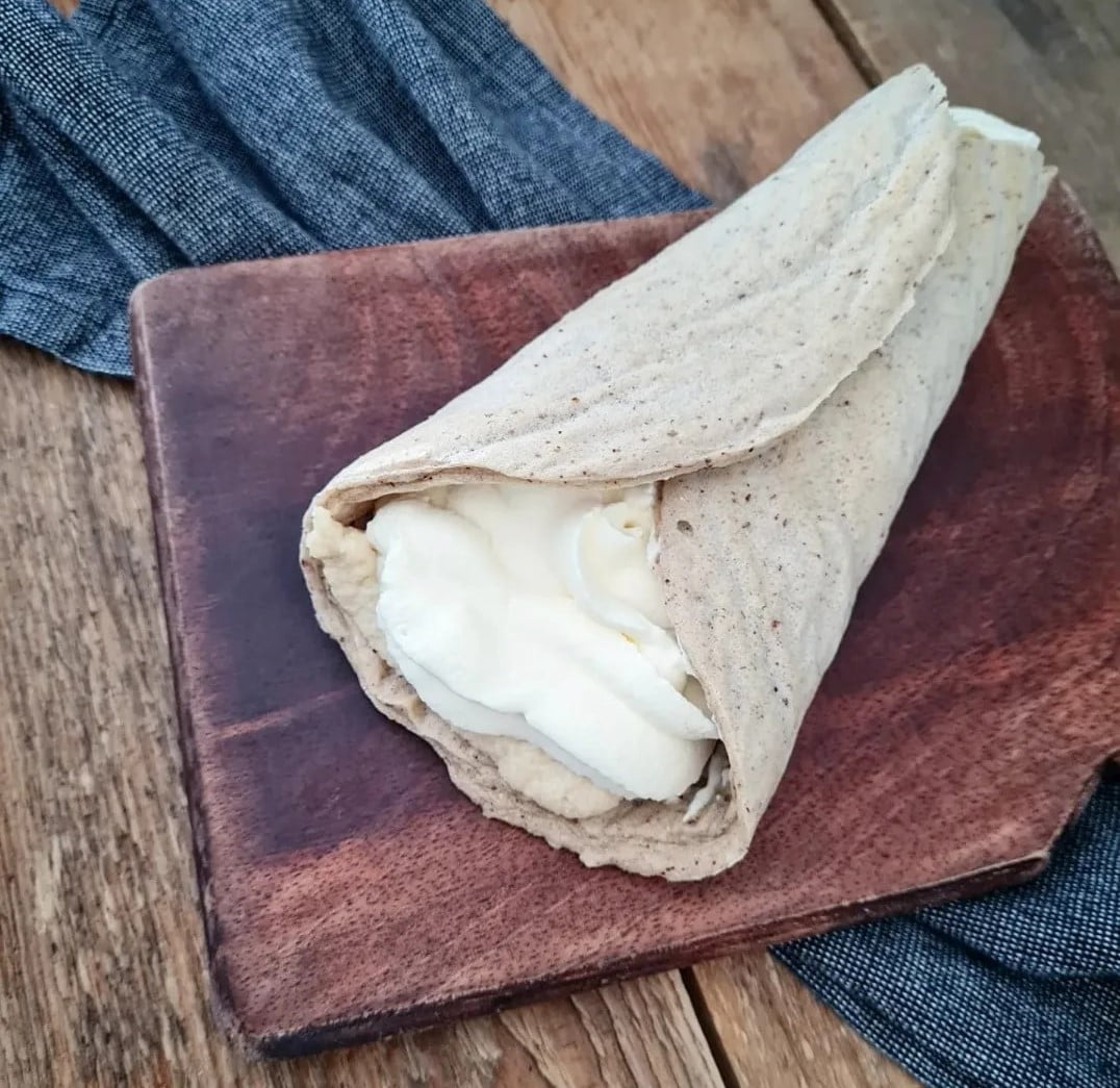 Wrap fylld med grädde inuti ett fullkornsbröd på en träskärbräda.